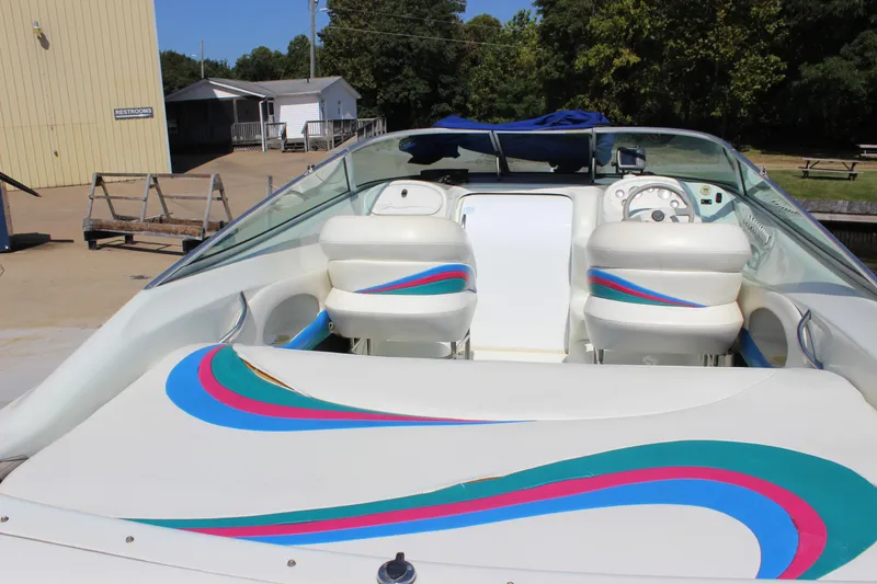 Slide: The Image of 1995 Baja 272 boat interior with colorful seating and dashboard, docked near a building. - 10