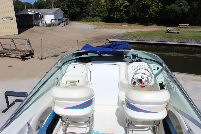 Slide: The Image of 1995 Baja 272 boat interior with white seating and steering wheel at a dock. - 11