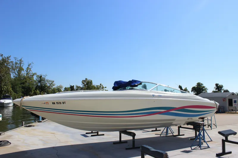 Slide: The Image of 1995 Baja 272 boat on stands, vibrant stripes, clear blue sky background. - 2
