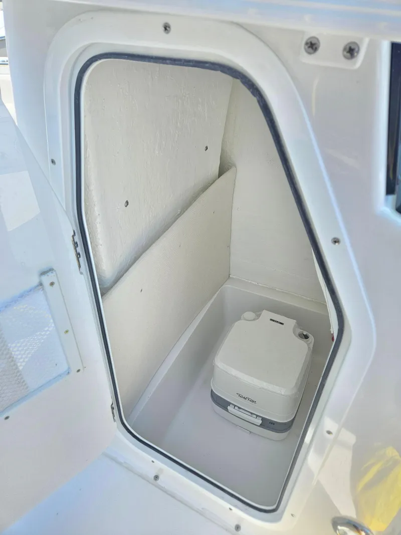 Slide: The Image of 2026 Sea Hunt Ultra 234 boat compartment with portable toilet. - 19