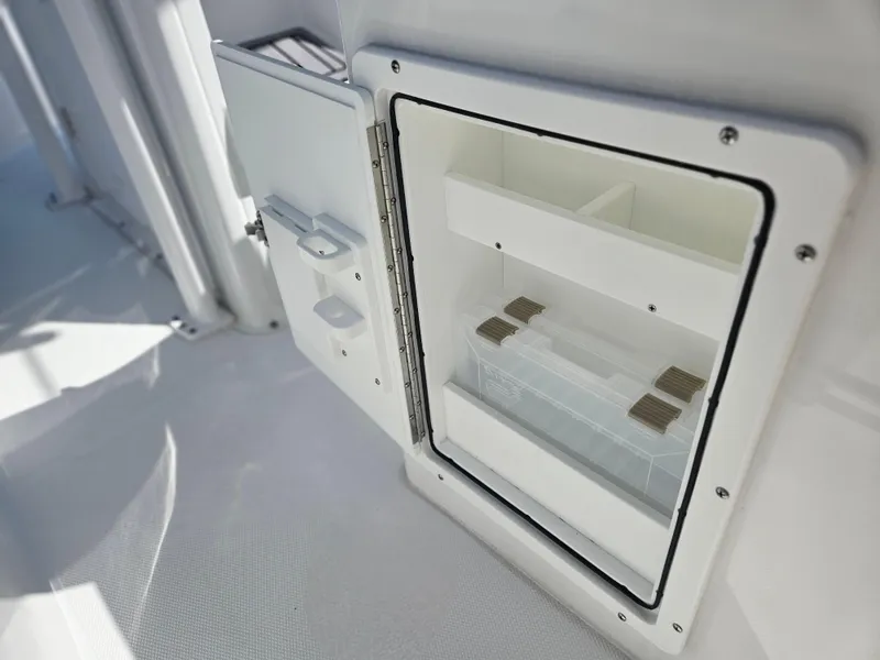 Slide: The Image of 2026 Sea Hunt Ultra 234 boat storage compartment with open door, showcasing interior shelves. - 22