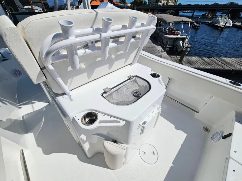 Slide: The Image of 2026 Sea Hunt Ultra 234 boat interior with rod holders and livewell, docked by the water. - 27