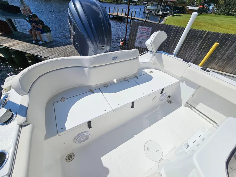 Slide: The Image of 2026 Sea Hunt Ultra 234 boat interior with seating and storage, docked by a scenic waterfront. - 28