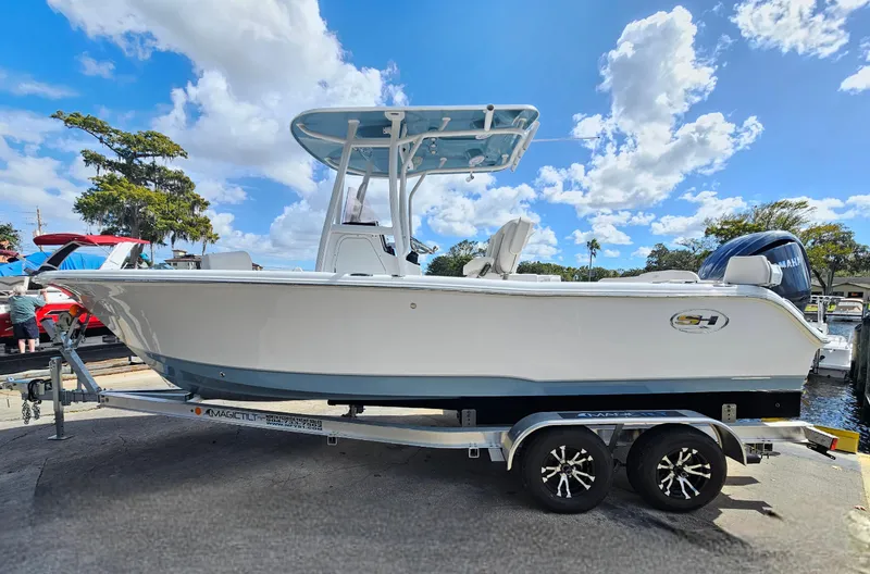 Slide: The Image of 2026 Sea Hunt Ultra 234 boat on trailer under a bright blue sky. - 6