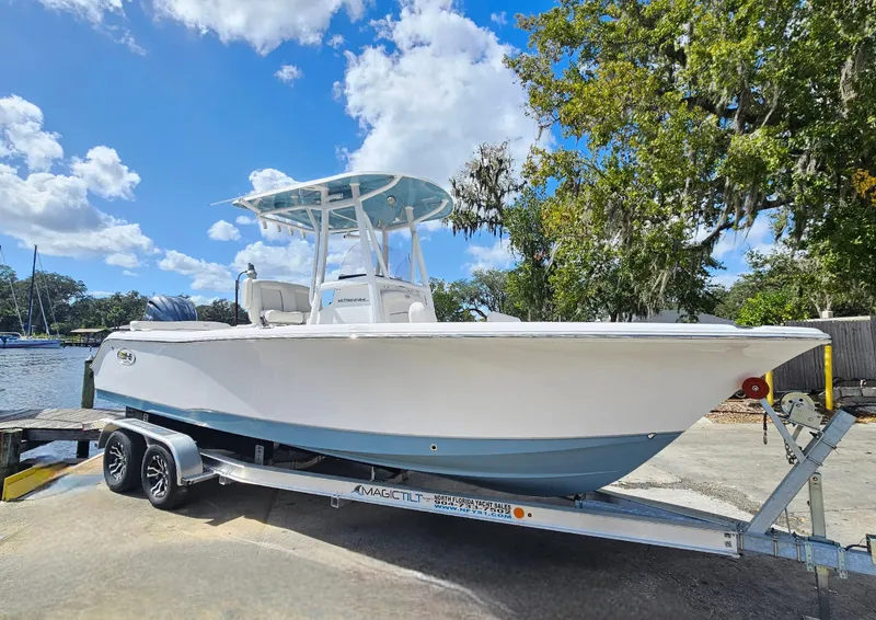 Slide: The Image of 2026 Sea Hunt Ultra 234 boat on trailer, parked near water under blue sky. - 1
