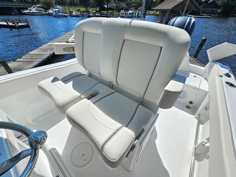 Slide: The Image of 2026 Sea Hunt Ultra 234 boat with white cushioned seating by a dock. - 21
