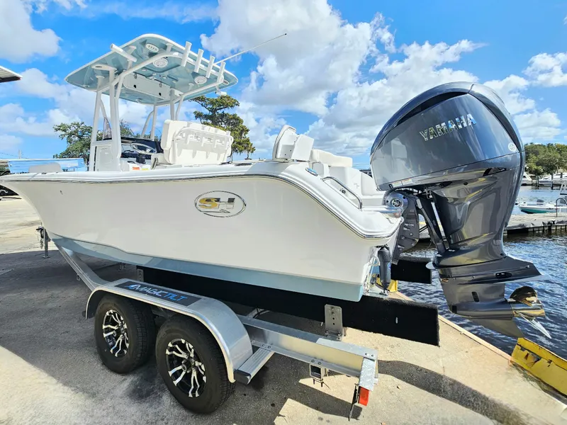 Slide: The Image of 2026 Sea Hunt Ultra 234 boat on trailer, featuring Yamaha outboard motor, under a blue sky. - 3