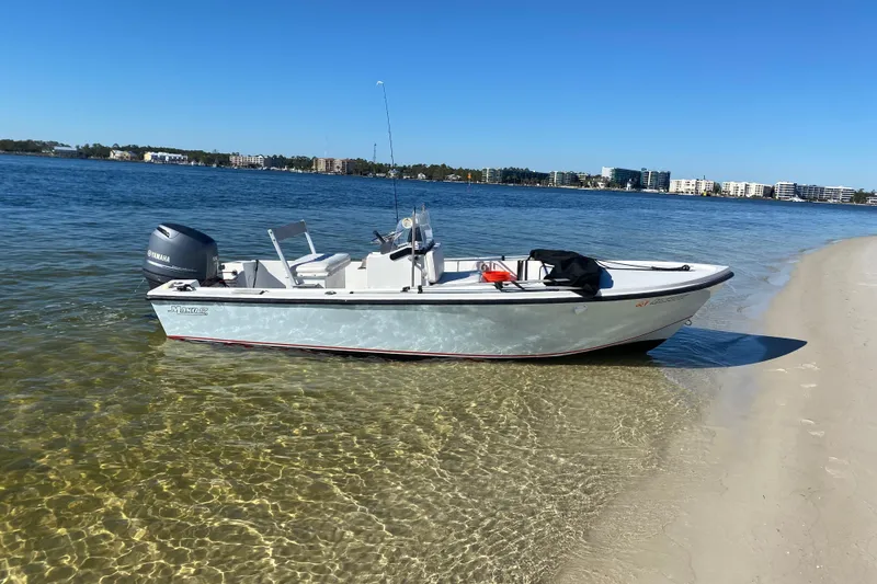 Slide: The Image of 1989 Mako 171 Center Console boat on sandy shore with clear water and blue sky. - 2