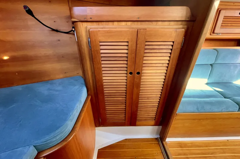 Slide: The Image of Wooden interior of a 1995 Freedom 35 sailboat with blue cushions and louvered cabinet doors. - 25