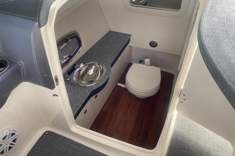 Slide: The Image of 2015 Chaparral 307 SSX boat interior with sink and toilet in compact bathroom. - 7