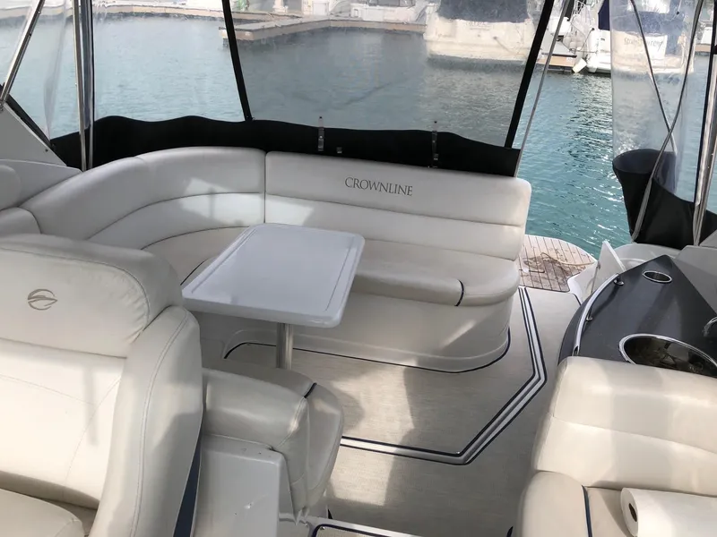 Slide: The Image of 2008 Crownline 340 CR yacht interior with white seating and table, docked by the water. - 11