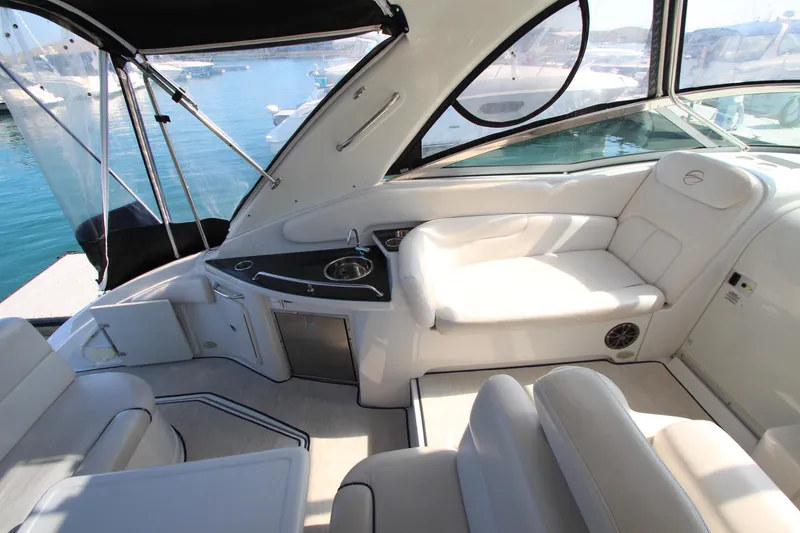 Slide: The Image of 2008 Crownline 340 CR yacht interior with white seating and kitchenette, docked by the water. - 18