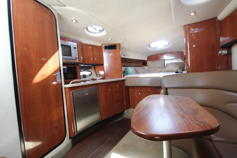 Slide: The Image of 2008 Crownline 340 CR cabin interior with wood finishes, kitchenette, and seating area. - 26