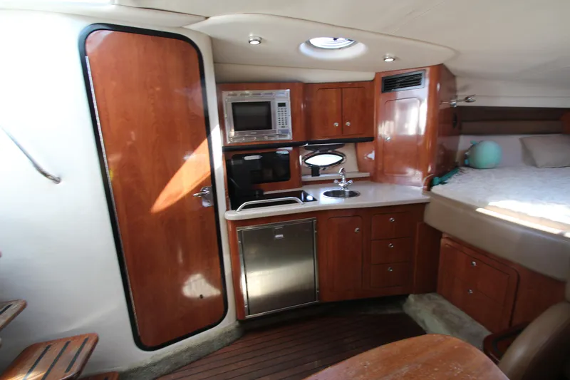Slide: The Image of 2008 Crownline 340 CR cabin interior with kitchenette, wood cabinetry, and bed. - 27