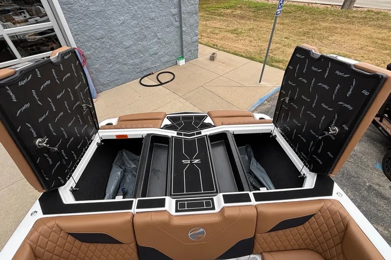 Slide: The Image of 2026 Tigé Z5 boat interior with open storage compartments and brown quilted seats. - 35