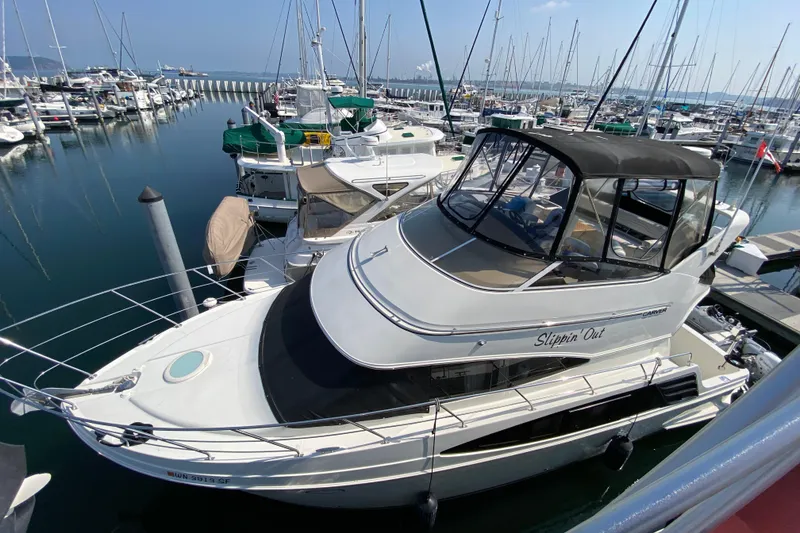Slide: The Image of 2004 Carver 36 Super Sport yacht docked in a marina, surrounded by other boats. - 2