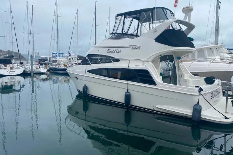 Slide: The Image of 2004 Carver 36 Super Sport yacht docked in a marina, surrounded by sailboats. - 75
