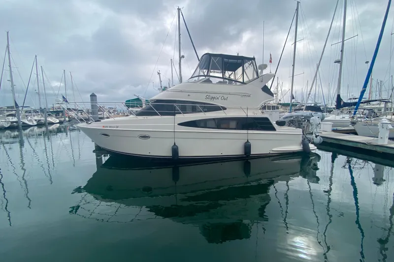 Slide: The Image of 2004 Carver 36 Super Sport yacht docked in a marina, reflecting on calm water. - 76