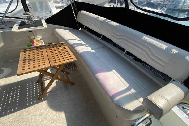 Slide: The Image of 2004 Carver 36 Super Sport yacht interior with cushioned seating and wooden table. - 44