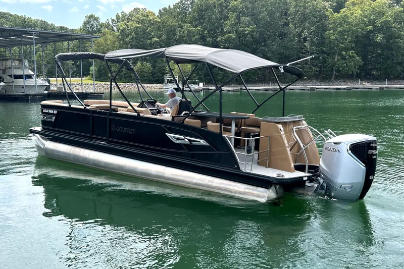 Slide: The Image of 2025 Godfrey AquaPatio Entertainment 255 CBE pontoon boat on a serene lake. - 4