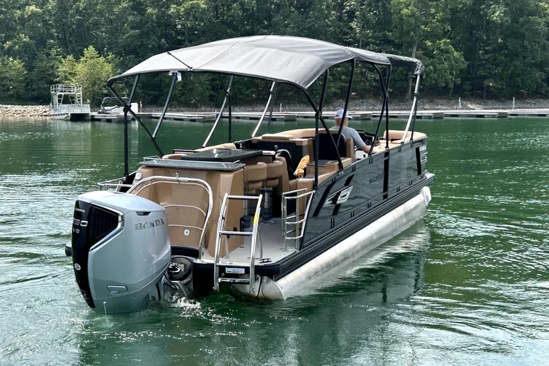 Slide: The Image of 2025 Godfrey AquaPatio Entertainment 255 CBE pontoon boat on a serene lake. - 6