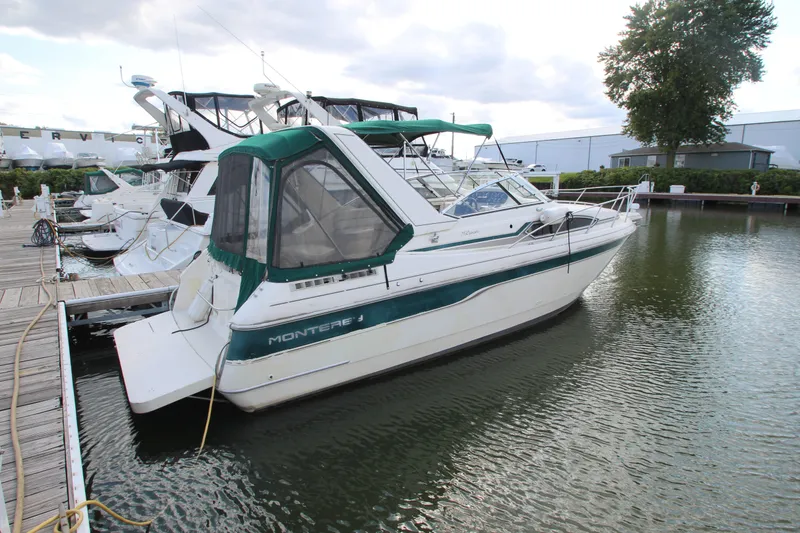 The Image of 1996 Monterey 296 Cruiser docked at marina, featuring green and white design. - 0