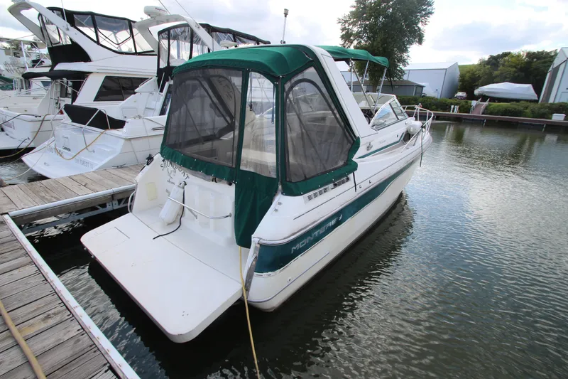 Slide: The Image of 1996 Monterey 296 Cruiser docked at marina, featuring green canopy and white hull. - 2