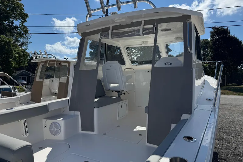 Slide: The Image of 2025 NorthCoast 255 HT boat interior with seating and helm, under a clear blue sky. - 10