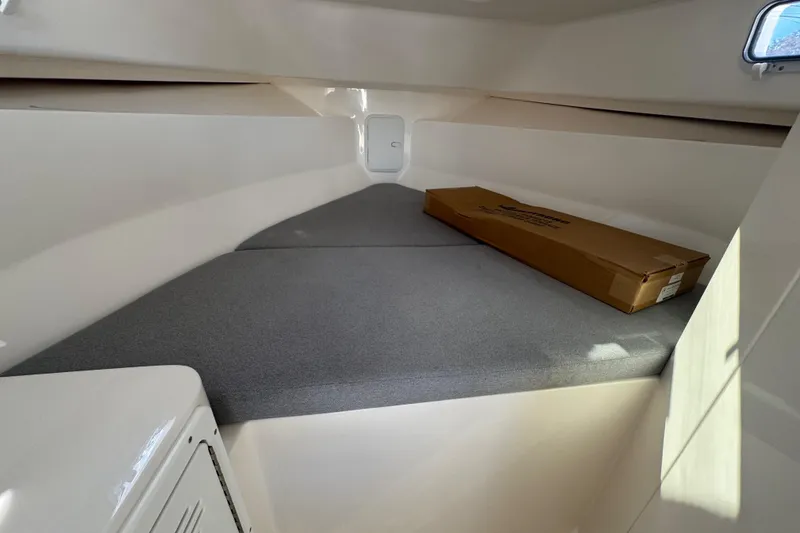 Slide: The Image of Interior cabin of 2025 NorthCoast 255 HT boat with gray cushions and a cardboard box. - 19