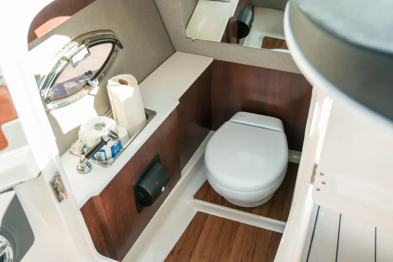 Slide: The Image of 2023 Chaparral 287 SSX boat bathroom with toilet, sink, and wooden accents. - 16