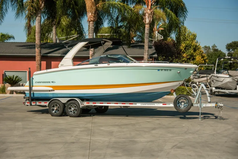 Slide: The Image of 2023 Chaparral 287 SSX boat on trailer, parked outdoors with palm trees. - 23