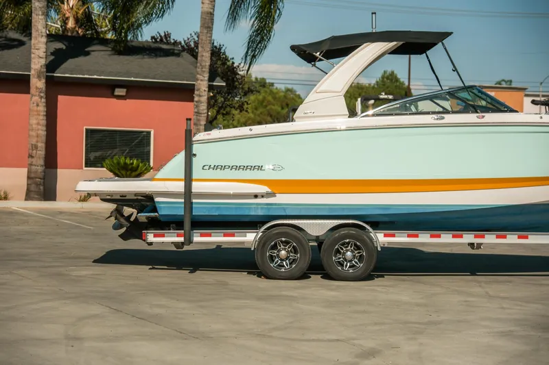 Slide: The Image of 2023 Chaparral 287 SSX boat on trailer, parked outdoors with palm trees. - 25