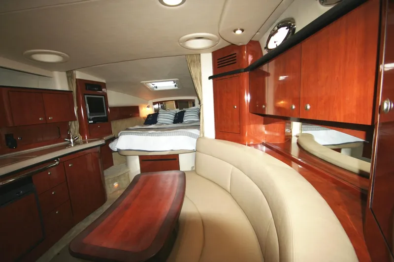 Slide: The Image of 2007 Sea Ray 320 Sundancer cabin interior with bed, wood cabinetry, and seating area. - 14