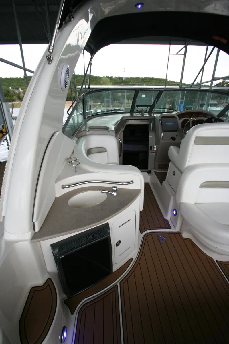 Slide: The Image of 2007 Sea Ray 320 Sundancer interior with white seating and wood flooring in a marina setting. - 39