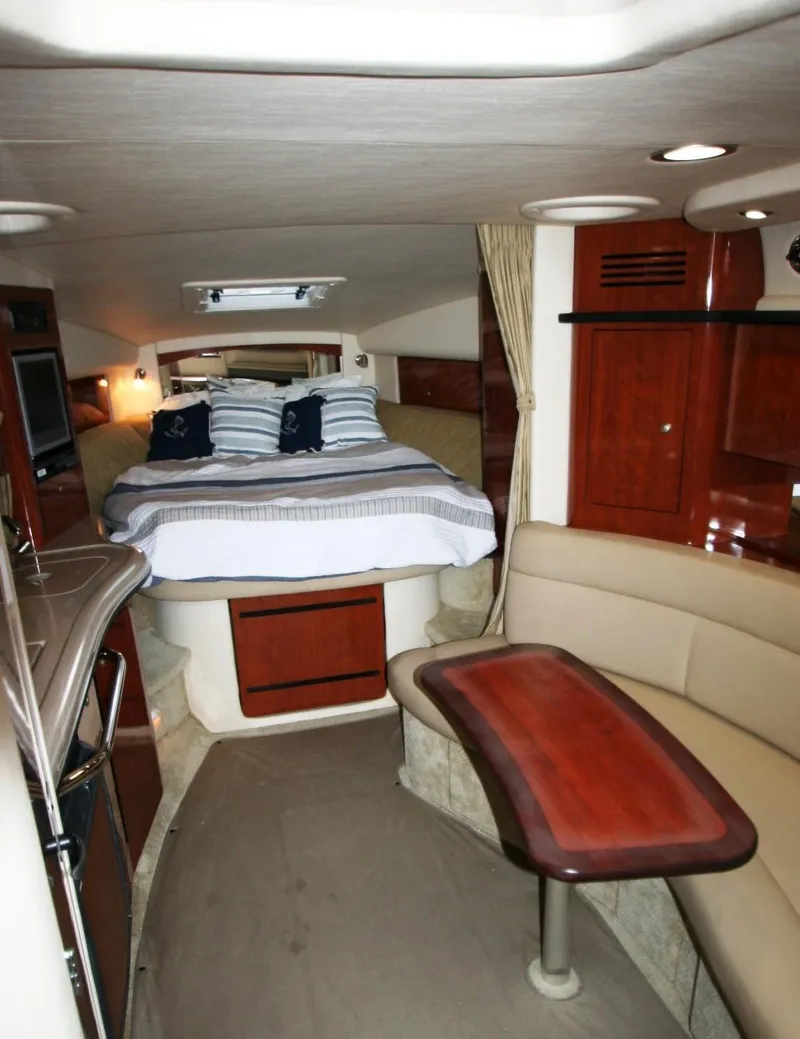 Slide: The Image of 2007 Sea Ray 320 Sundancer cabin interior with bed, seating, and wooden table. - 4