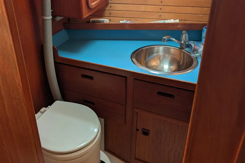 Slide: The Image of 1987 Cascade Center Cockpit bathroom with blue countertop, stainless steel sink, and wooden cabinetry. - 32