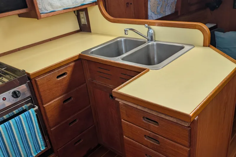 Slide: The Image of 1987 Cascade Center Cockpit kitchen with dual sink, wooden cabinets, and stove. - 42