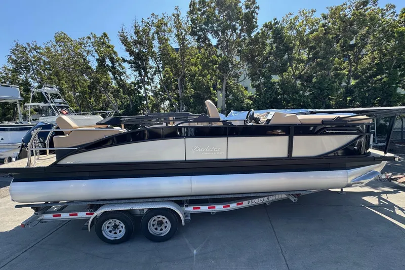 Slide: The Image of 2026 Barletta Cabrio 24UE pontoon boat on trailer, parked outdoors. - 3