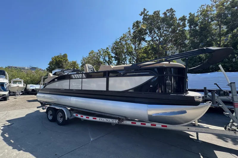 Slide: The Image of 2026 Barletta Cabrio 24UE pontoon boat with canopy, parked outdoors. - 4