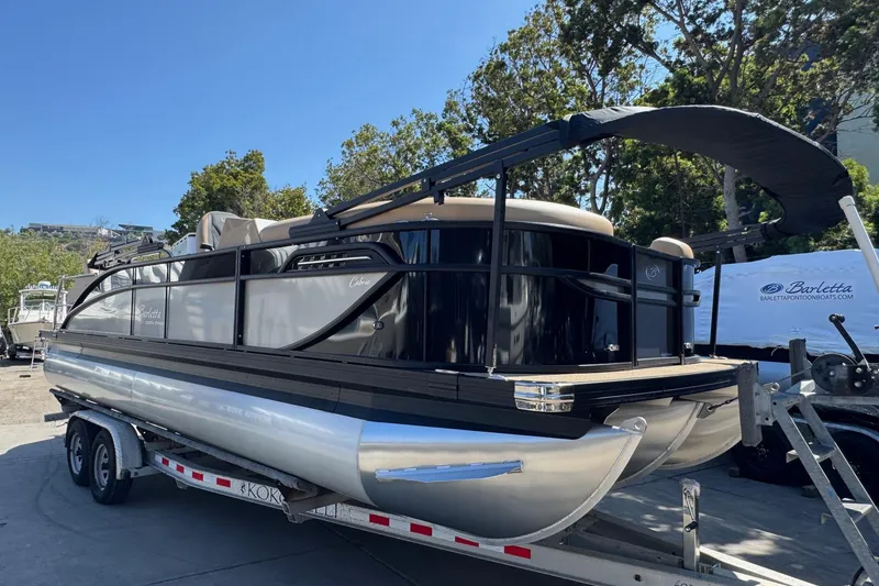 Slide: The Image of 2026 Barletta Cabrio 24UE pontoon boat on trailer, parked outdoors. - 6