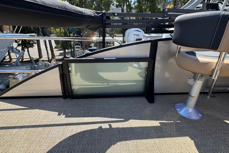 Slide: The Image of 2026 Barletta Cabrio 24UE boat interior with seating and table, surrounded by trees. - 63