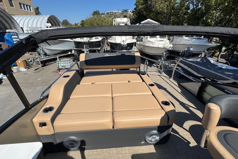 Slide: The Image of 2026 Barletta Cabrio 24UE boat with tan seating and cup holders, docked outdoors. - 79