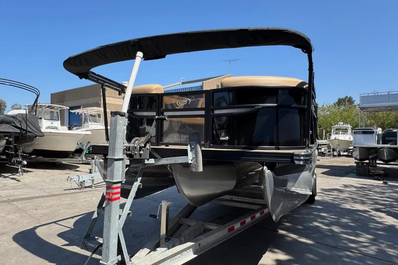 Slide: The Image of 2026 Barletta Cabrio 24UE pontoon boat on trailer, parked outdoors under clear blue sky. - 8