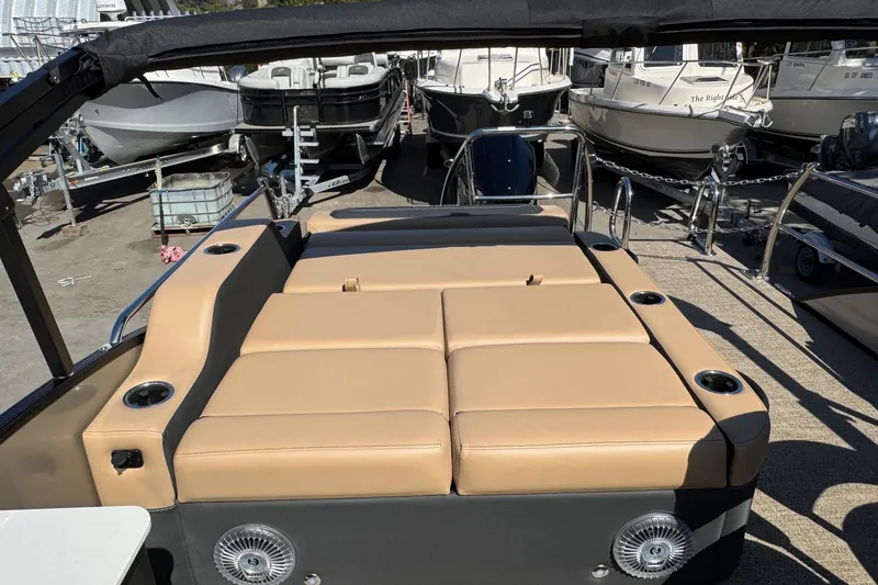 Slide: The Image of 2026 Barletta Cabrio 24UE boat with tan seating and cup holders, docked among other boats. - 80