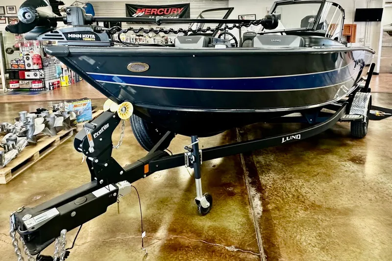 Slide: The Image of 2026 Lund 1875 Crossover XS boat on trailer in showroom, featuring Minn Kota Terrova motor. - 1