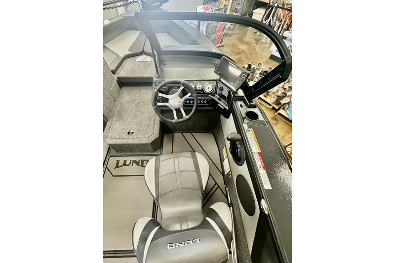 Slide: The Image of 2026 Lund 1875 Crossover XS boat interior with steering wheel and dashboard controls. - 12