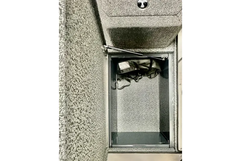 Slide: The Image of Storage compartment of 2026 Lund 1875 Crossover XS boat, featuring carpeted interior. - 14