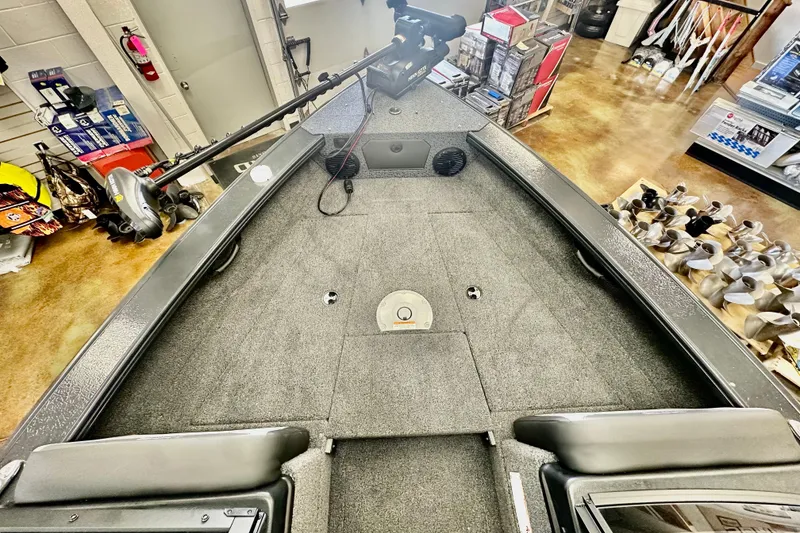 Slide: The Image of 2026 Lund 1875 Crossover XS boat interior with carpeted deck in showroom. - 17