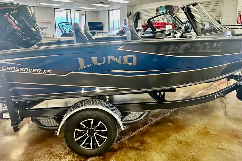 Slide: The Image of 2026 Lund 1875 Crossover XS boat displayed indoors on a trailer. - 5