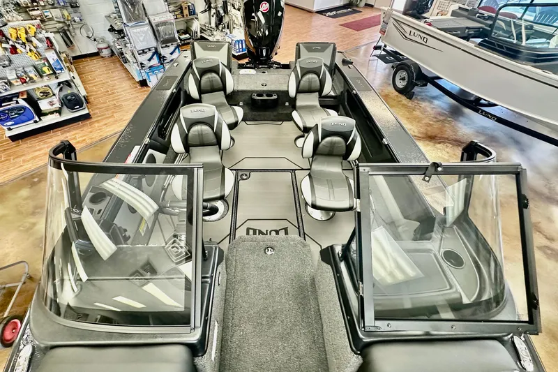 Slide: The Image of 2026 Lund 1875 Crossover XS boat interior with seating and windshield in showroom. - 8